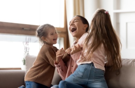 Woman holding the hands of two girl children and laughing